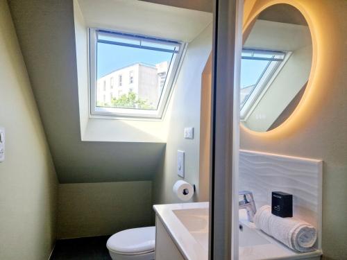 une salle de bain avec une fenêtre, un lavabo et des toilettes dans l'établissement L'Ermitage Cosy, à Cherbourg en Cotentin