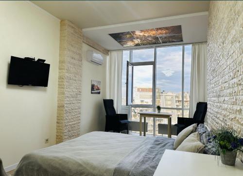 a bedroom with a bed and a window with a table and chairs at Apartments Arcadia VIP in Odesa