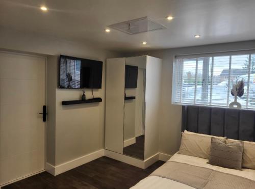 a bedroom with a bed and a tv and a window at Trendy Studio With A Private Garden in Chatham