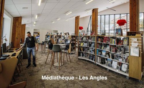 a man standing in a library with books on shelves at Chalet Vue sous cet Angles in Les Angles