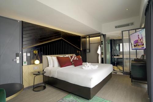 a bedroom with a large white bed and a television at Awann Sewu Boutique Hotel and Suite Semarang in Semarang