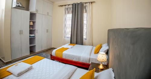 a small bedroom with two beds and a window at Luxury 2BR Apartment with AC, Wi Fi, Backup Power Ideal for Families , Bukoto in Kampala
