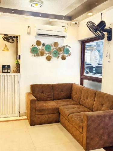 a brown couch in a living room with plates on the wall at Hotel Shadow Regency in Ernakulam