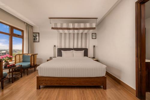 a bedroom with a bed and a chair and a window at HA Ocean Front Hotel and Apartment in Hoi An