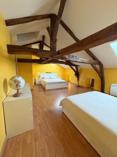 deux lits dans une chambre aux murs jaunes et aux poutres en bois dans l'établissement La Bourgeoise, à Neuvic