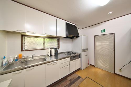 a kitchen with white cabinets and a sink at 楽宿 藤花 046h in Hakone