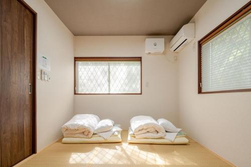 two beds in a room with a window at 楽宿 藤花 046h in Hakone
