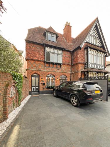 a black car parked in front of a brick house at Incredible Luxury Windsor Long Walk 4 Bedroom Home With Free Driveway Parking in Windsor