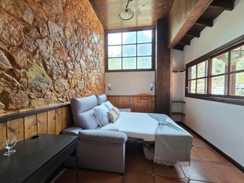 a room with a bed and a couch and a stone wall at Tamahuche Hotel Rural in Vallehermoso