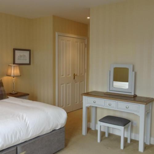a bedroom with a bed and a desk with a tv on it at Loch Ness Lodge in Drumnadrochit