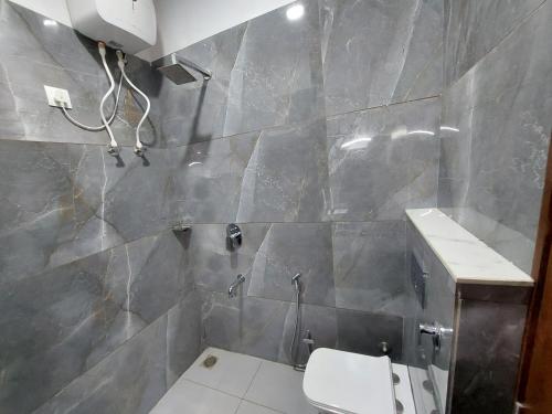 a bathroom with a toilet and a tile wall at Hotel Kesari in Sālāsar
