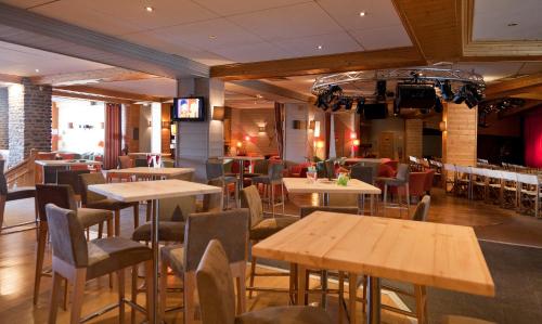 a restaurant with tables and chairs and a television at Hôtel Club mmv Altitude **** in Arc 2000