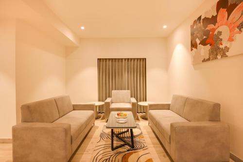 a living room with two couches and a table at Lemon Tree Hotel, Jamnagar in Jamnagar