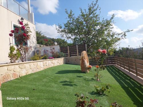 a garden with green grass and a retaining wall at Afroditi 2 in Angón