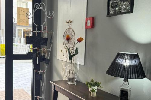 a table with a lamp and a vase with flowers on it at Hotel Bologna in Rimini
