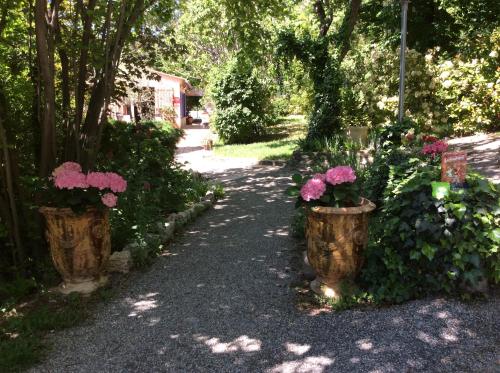 a walkway with two buckets of flowers and trees at Clos des Iris in Moustiers-Sainte-Marie