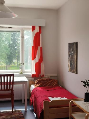 a bedroom with a bed and a desk and a window at Jennin Majatalo in Reisjärvi