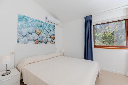 a white bedroom with a bed and a window at Seafront House Bamba - Sea view and Nature in Capo Coda Cavallo