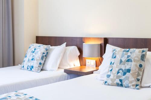 a bedroom with two beds with pillows and a lamp at Hotel Olympia Universidades in Valencia
