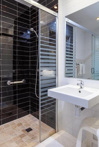 a bathroom with a sink and a glass shower at Hotel Olympia Universidades in Valencia