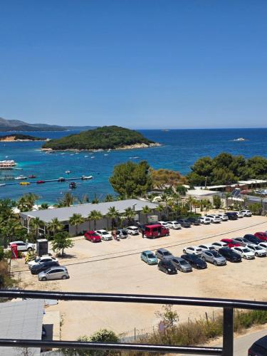 a parking lot with parked cars and the ocean at Elio's Rooms in Ksamil