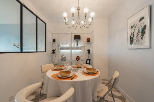 une salle à manger avec une table, des chaises et un lustre dans l'établissement La Résidence des deux Plages, à Saint-Georges-de-Didonne
