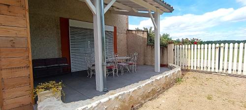 a patio with a table and chairs and a fence at Le Reflet du Trèfle in Puybegon