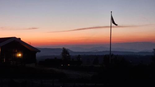 a flag on a pole in front of a sunset at Langleiken in Sør-Fron