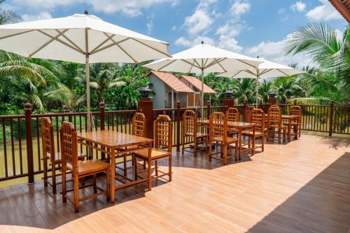 a row of tables and chairs with umbrellas on a deck at Le Palmier Long An Boutique Resort - Free Outdoor Cinema in Ấp Kế Mỹ