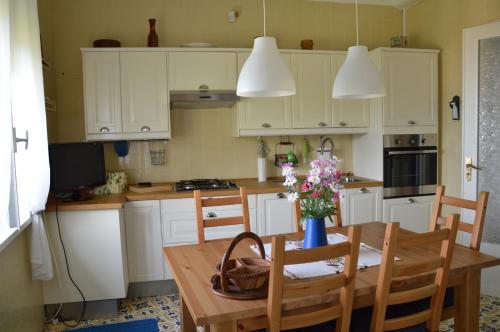 una cucina con armadi bianchi e un tavolo in legno con fiori di Villa Bouganvilla a Cefalù