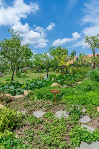 a sign in the middle of a garden at Le Palmier Long An Boutique Resort - Free Outdoor Cinema in Ấp Kế Mỹ