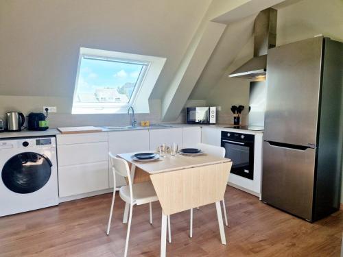 une cuisine avec une table, des chaises et un réfrigérateur dans l'établissement L'Ermitage Smart, à Cherbourg en Cotentin