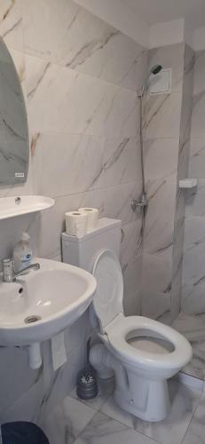 a white bathroom with a toilet and a sink at Casa Călin in Vama Veche