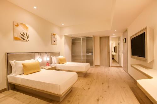 a hotel room with two beds and a television at Lemon Tree Hotel, Jamnagar in Jamnagar