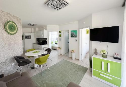 a living room with a table and chairs and a tv at TemOro Apartman Green in Siófok