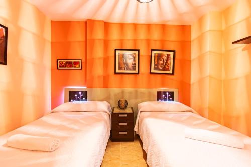 Dos camas en una habitación con paredes naranjas. en Playa de Levante, Céntrico y Parking - by Aloha Palma, en Águilas