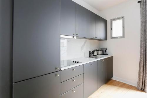 une cuisine avec des armoires blanches et un évier dans l'établissement Marvelous 2 bedrooms - Saint Honore - Palais Royal, à Paris