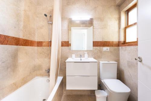 a bathroom with a toilet and a sink and a tub at Casa Malo Garden and sea view townhouse in La Jaca