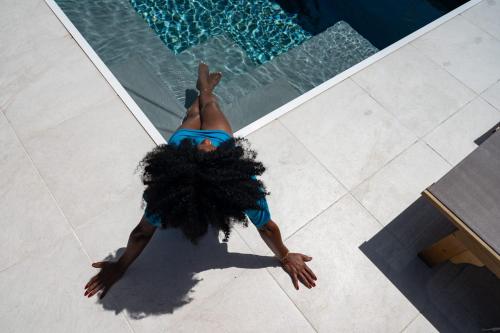a woman laying on the floor next to a swimming pool at Villa Jacaranda in Capesterre-de-Marie-Galante