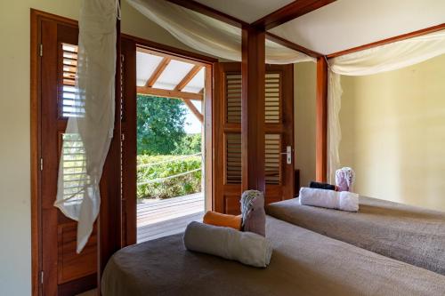 two beds in a room with a large window at Villa Jacaranda in Capesterre-de-Marie-Galante