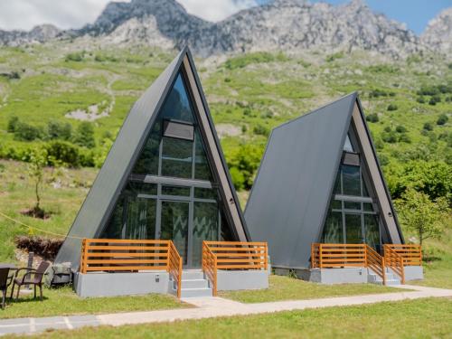 Un edificio con bancos y montañas al fondo. en Arditi's Chalets, en Bogë