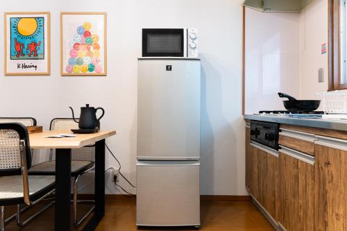 a white refrigerator in a kitchen with a table at Animal Art Apartment Type 12 in Tokyo