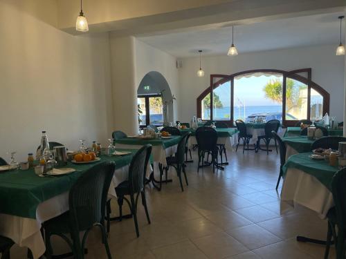 a dining room with tables and chairs with green tablecloths at Hotel Miramare Garzia in Marinella di Selinunte
