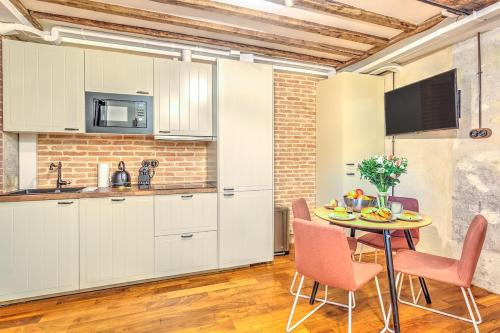 une cuisine avec des armoires blanches et une table et des chaises dans l'établissement Industrial loft - Le Marais - Bastille, à Paris