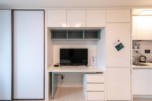 a kitchen with white cabinets and a desk with a television at The November Stay In landmark in Incheon