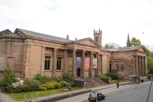 a large brick building on a city street at Townhead Apartments Gallery View in Paisley