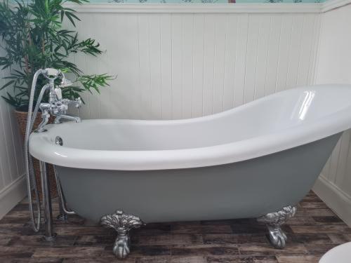 a white bath tub in a bathroom with a plant at Eagle View Guest House in Newtonmore