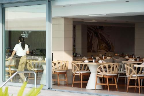 a woman walking through a window of a restaurant at Marins Suites - Adults Only Hotel in Cala Millor