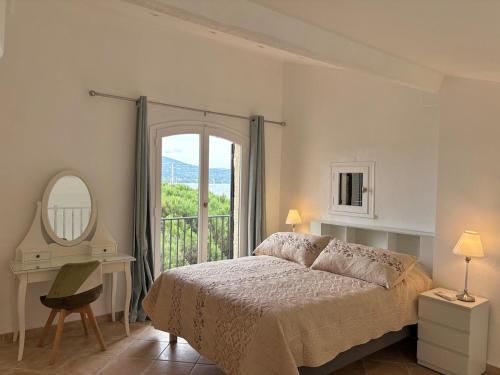 une chambre avec un lit, un miroir et une fenêtre dans l'établissement Les Tropéziennes - Chic Triplex Balcon Vue Marina, à Cogolin