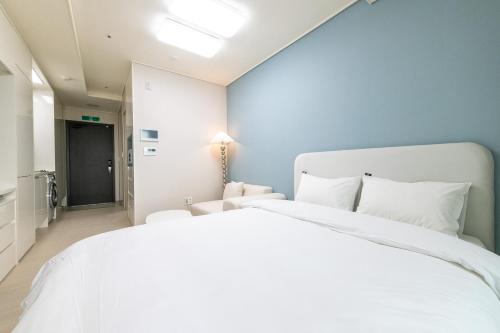 a bedroom with a white bed and a blue wall at The November Stay In landmark in Incheon